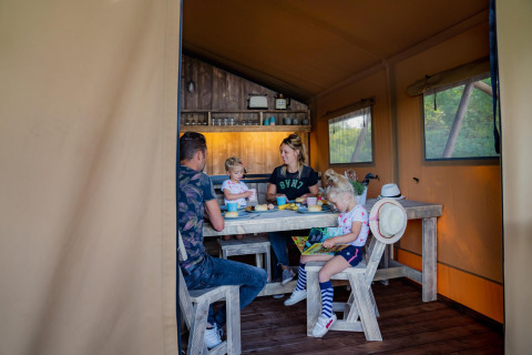 Gezin aan tafel in houten lodge bij Water Lodge WL, Holiday Park BreeBronne, Nederland.