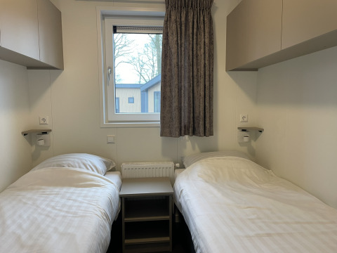 Twee eenpersoonsbedden in een Wood Cottage bij vakantiepark De Witte Berg, Nederland, centraal raam.