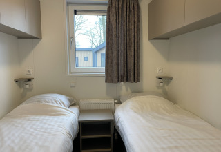 Twee eenpersoonsbedden in een Wood Cottage bij vakantiepark De Witte Berg, Nederland, centraal raam.