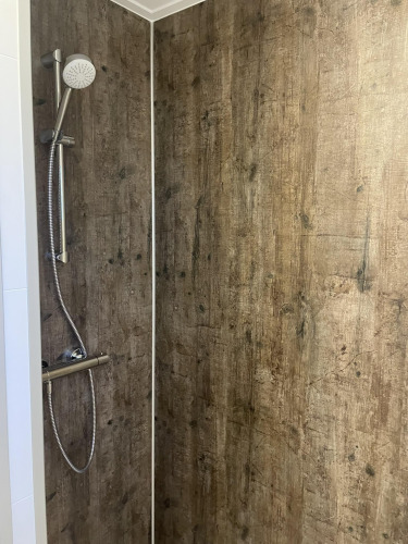 Ducha con paredes de aspecto madera en Wood Cottage del Holiday park De Witte Berg, Países Bajos.