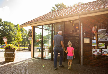 Ein älterer Mann und ein Mädchen betreten gemeinsam das Wood Cottage im Ferienpark De Witte Berg, Niederlande.