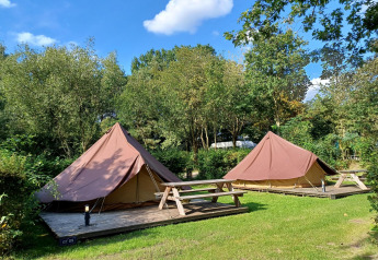 Twee Glamptent GT tenten met picknicktafels in Holiday Park BreeBronne, Nederland, omgeven door groen.