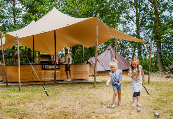 Zwei Mädchen spielen vor einer Glamptent GT Lodge im Holiday Park BreeBronne in den Niederlanden.
