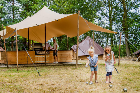 Zwei Mädchen spielen vor einer Glamptent GT Lodge im Holiday Park BreeBronne in den Niederlanden.