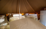 Vista interior de Glamptent GT en Holiday Park BreeBronne, Países Bajos, con camas y nevera pequeña.