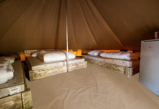 Vista interior de Glamptent GT en Holiday Park BreeBronne, Países Bajos, con camas y nevera pequeña.