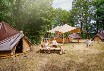 Family enjoys camping outside Glamptent GT at Holiday Park BreeBronne in the Netherlands with tents visible.