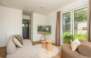 Cozy living room at Wellness Lodge with modern sofas, wooden tables and garden views in Vakantiepark Hölte.