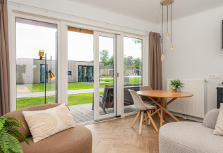 Soggiorno luminoso in una Wellness Lodge con arredo moderno, accesso alla terrazza e vista sui prati verdi.