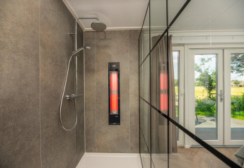 Ducha moderna con pared de cristal, panel infrarrojo y vista al jardín en Wellness Lodge, Vakantiepark Hölte.