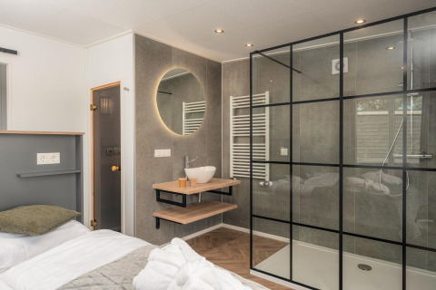 Moderne Wellness Lodge med glasbrusekabine, vask og hyggelig indretning på Vakantiepark Hölte, Holland.