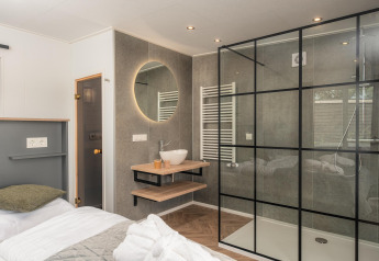 Moderne Wellness Lodge med glasbrusekabine, vask og hyggelig indretning på Vakantiepark Hölte, Holland.