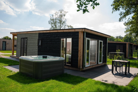 Wellness Lodge med jacuzzi og sauna på Vakantiepark Hölte i Holland, moderne træhytte i grønne omgivelser.