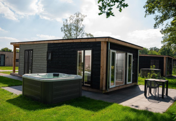 Wellness Lodge med jacuzzi og sauna på Vakantiepark Hölte i Holland, moderne træhytte i grønne omgivelser.