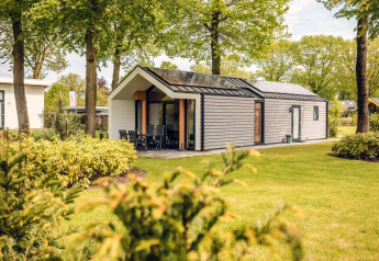Modern lodge called Ecovilla at Holiday park Ackersate in the Netherlands, surrounded by lawns and trees.