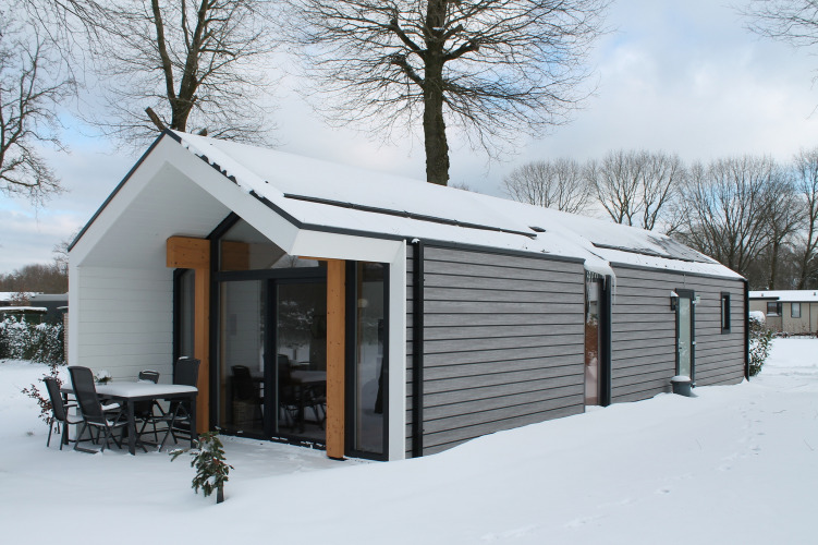 Ecovilla lodge at Holiday park Ackersate in the Netherlands, with a snowy roof and modern exterior.