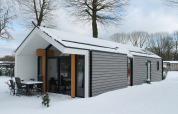 Ecovilla-lodge bij Holiday park Ackersate in Nederland, met besneeuwd dak en moderne buitenkant.