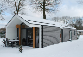 Ecovilla-lodge bij Holiday park Ackersate in Nederland, met besneeuwd dak en moderne buitenkant.