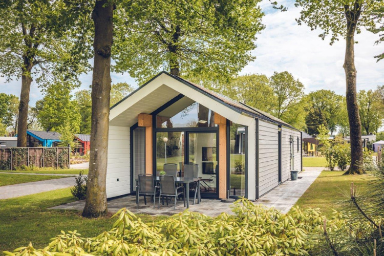 Ecovilla lodge at Holiday park Ackersate in the Netherlands, surrounded by green trees and outdoor seating.