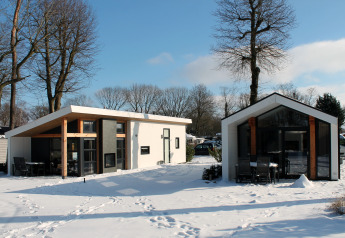 Zwei moderne Lodges namens Ecovilla im Holiday park Ackersate, Niederlande, im verschneiten Winter.