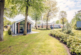 Ecovilla-Lodge im Holiday Park Ackersate in den Niederlanden, umgeben von Bäumen und viel Grün.