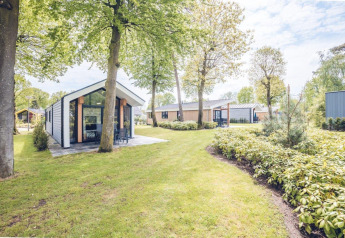 Ecovilla-lodge bij Holiday park Ackersate in Nederland, omgeven door grasvelden en groene bomen.