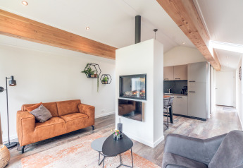 Moderne lodge med stue, pejs og køkken i Ecovilla på Feriepark Ackersate, Holland, lyst og rummeligt.