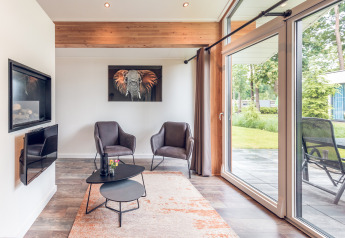 Soggiorno moderno in Ecovilla al Holiday park Ackersate, Paesi Bassi, con grandi finestre e arredi eleganti.