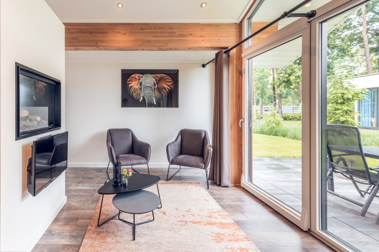 Modern lounge at Ecovilla in Holiday park Ackersate, Netherlands, with large windows, art and cozy seating.