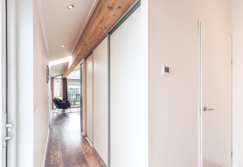Corridoio luminoso in Ecovilla al Holiday park Ackersate, Paesi Bassi, con dettagli in legno e arredi moderni.