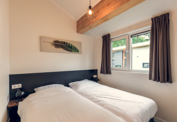 Schlafzimmer in der Ecovilla im Ferienpark Ackersate, Niederlande, mit zwei Einzelbetten und Fenster.