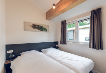 Dormitorio en Ecovilla de Holiday park Ackersate, Países Bajos, con dos camas individuales y ventana grande.