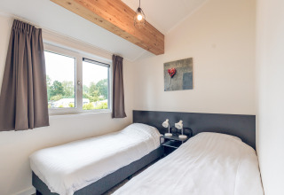 Habitación con dos camas individuales, ventana grande, decoración moderna en Ecovilla, Holiday Park Ackersate.