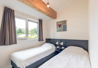 Habitación con dos camas individuales, ventana grande, decoración moderna en Ecovilla, Holiday Park Ackersate.