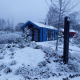 Sneklædt jagthytte og sauna ved Holiday park Ackersate i Holland, omgivet af vinterlige træer og buske.