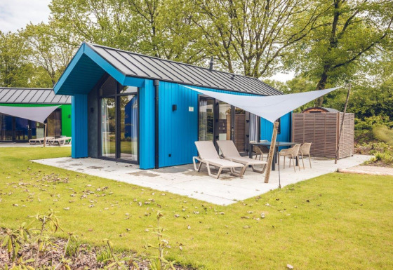 Blåt jagthytte med sauna og terrasse ved Holiday park Ackersate, omringet af grønt og have i Holland.