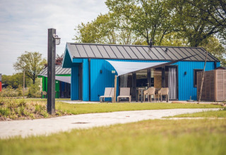 Moderno chalet de caza con sauna en Holiday park Ackersate, Países Bajos, rodeado de vegetación y césped.