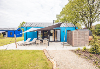 Hunting chalet with blue exterior, outdoor seating, sun loungers and sauna at Holiday park Ackersate, Netherlands.