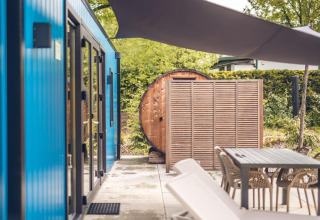 Buitenruimte bij een jachthut met sauna, moderne zitjes en blauwe gevel in Holiday park Ackersate.