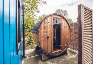 Outdoor round barrel sauna situated next to a lodge at Holiday park Ackersate in the Netherlands.