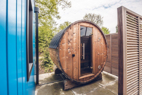 Outdoor round barrel sauna situated next to a lodge at Holiday park Ackersate in the Netherlands.