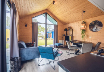 Moderne lodge med trævægge, store vinduer, komfortabel stue og spiseplads med udsigt til naturen.