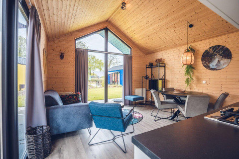 Modern lodge interior with wooden walls, large windows, cozy seating area, and a stylish dining space.