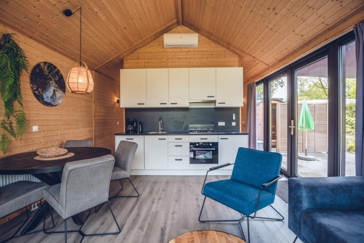 Moderne Lodge-Innenraum mit Küche, Essbereich, Holzwänden und großen Fenstern zur Terrasse.