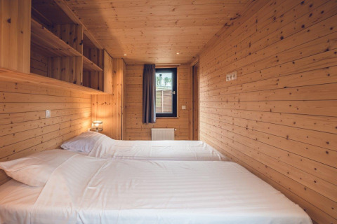 Habitación de madera con dos camas individuales en un acogedor chalet de caza con sauna en Holiday park Ackersate, Países Bajos.