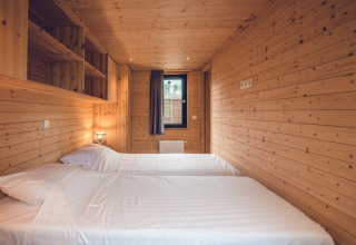 Habitación de madera con dos camas individuales en un acogedor chalet de caza con sauna en Holiday park Ackersate, Países Bajos.