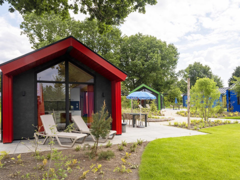 Chalet da caccia moderno all'Holiday park Ackersate, Paesi Bassi, con sdraio e ambiente verdeggiante.