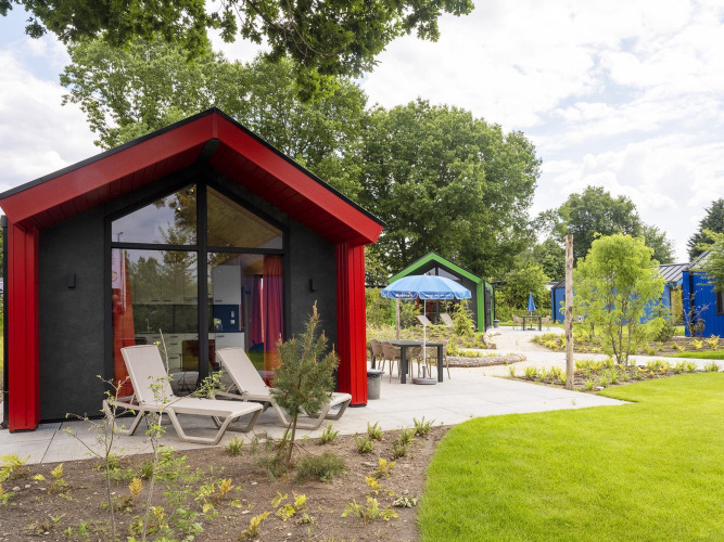 Modernes Jagdchalet im Holiday Park Ackersate, Niederlande, mit Sonnenliegen und grüner Gartenlandschaft.