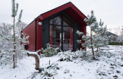Cabaña de caza roja en Holiday park Ackersate, Países Bajos, rodeada de nieve y pinos en invierno.