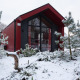 Cabaña de caza roja en Holiday park Ackersate, Países Bajos, rodeada de nieve y pinos en invierno.